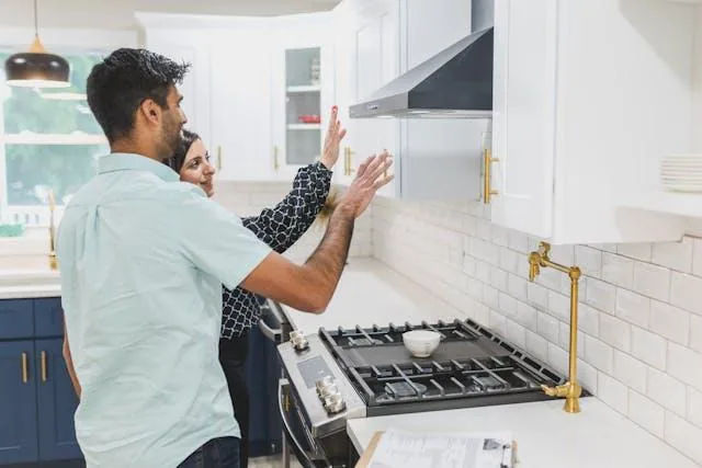 Two people inspecting a stove fan